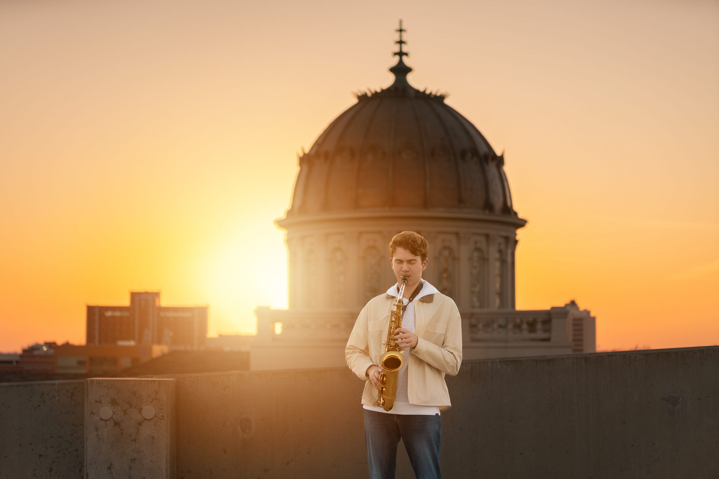 OKC Grad playing saxophone at sunset