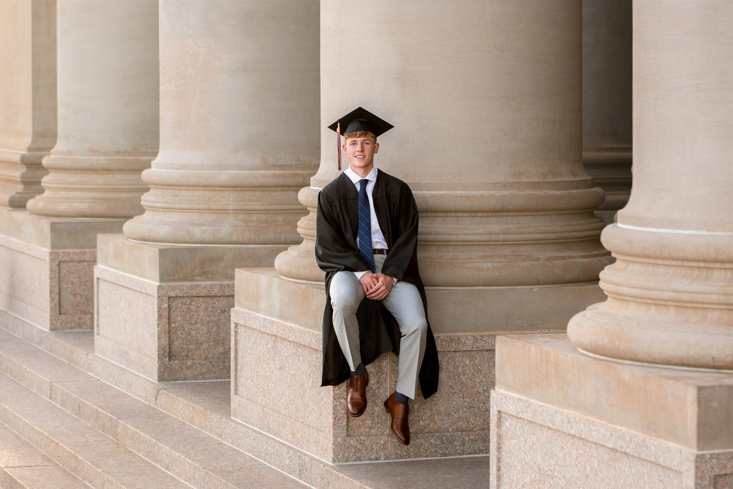 senior guy in cap and gown at the state capitol