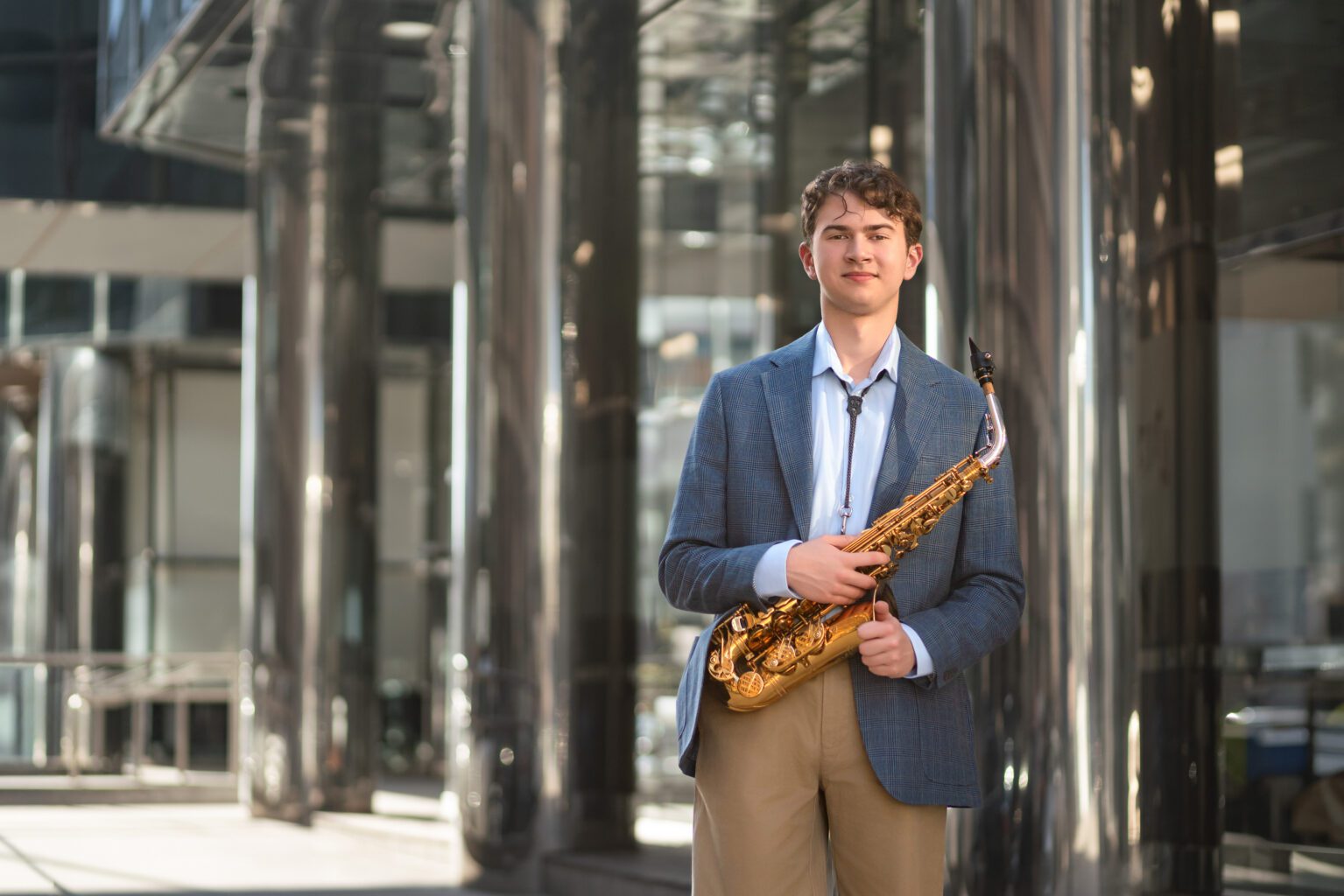 Senior Guy posing with a saxophone in Oklahoma city leadership Square for Urban senior photography
