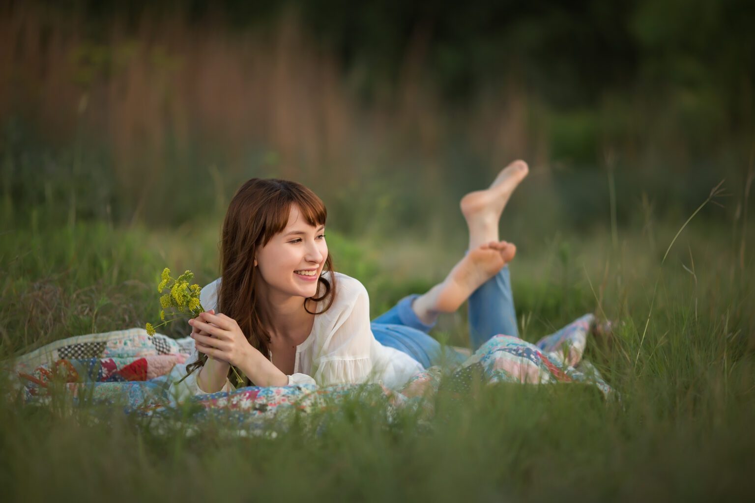 Girl on laying on the grass holding flowers for a senior session