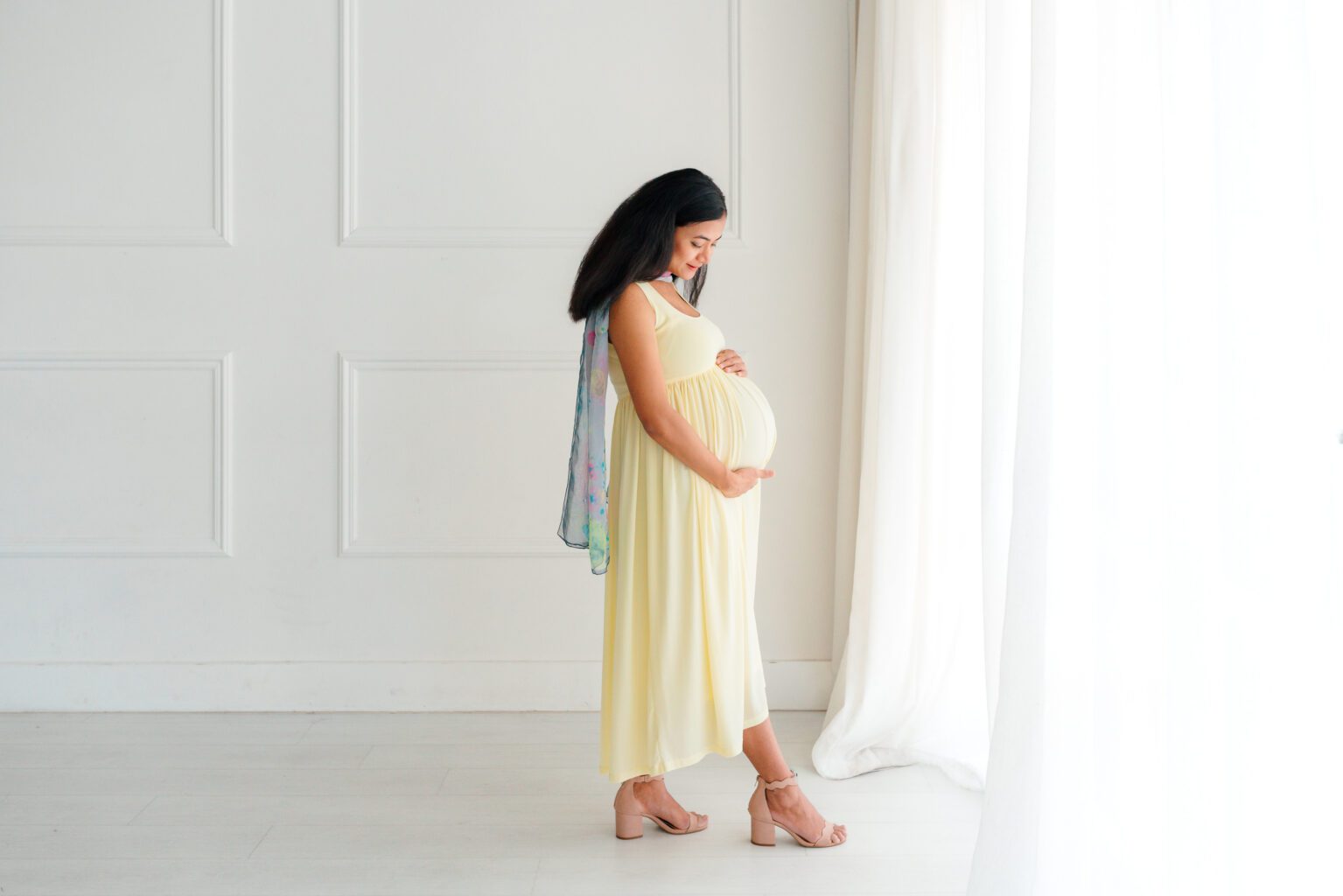 Pregnant woman in yellow dress posing for OKC maternity photographer session